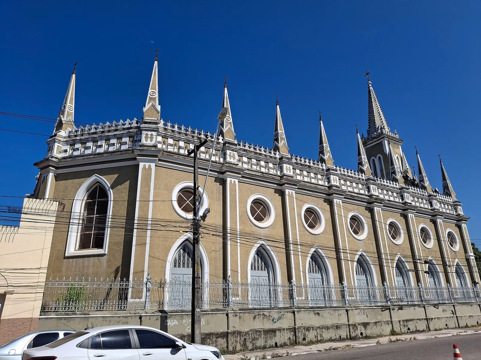 The long front of Igreja do Pequeno Grande with pointed pinnacles and round windows under a blue sky